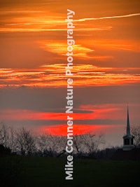 sunset over a church with a steeple in the background