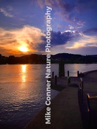 a sunset over a river with a dock in the background